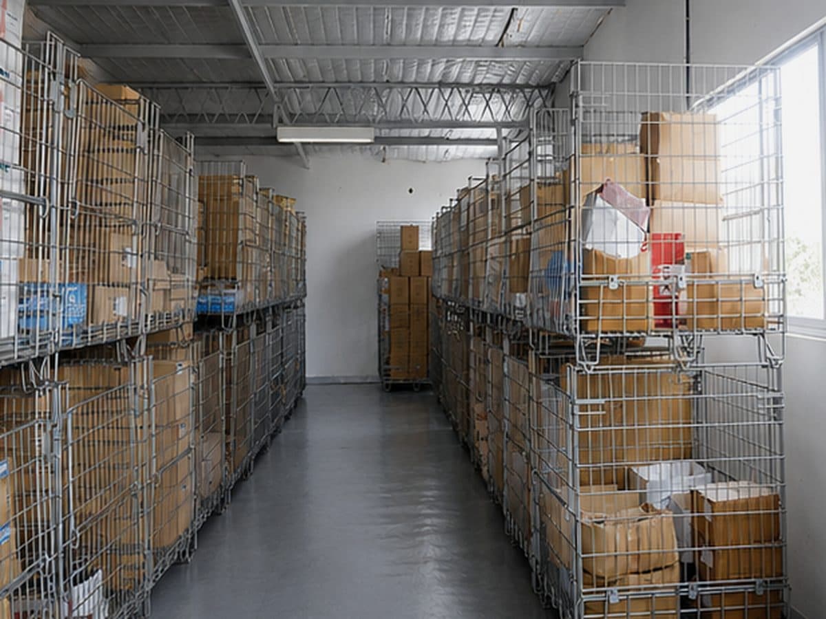 Depósito de la planta con contenedores y cajas en jaulas metálicas