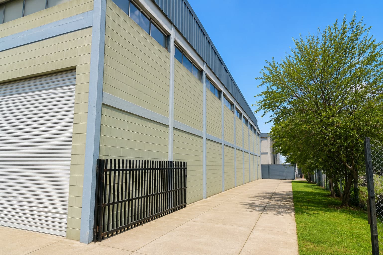 Fachada de una planta industrial junto a una vereda arbolada